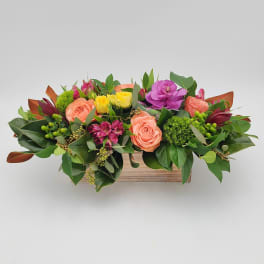 Mixed bouquet of roses and colorful blooms in a wooden box