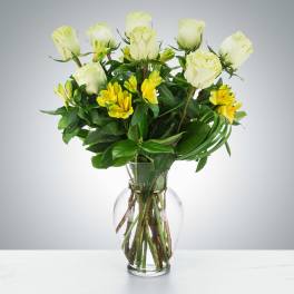 Arrangement of white roses and yellow alstroemeria in a clear glass vase
