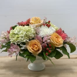Mixed bouquet of roses, hydrangeas, and daisies in a white vase