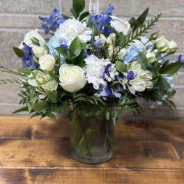 White and blue mixed flower arrangement in a clear glass vase.