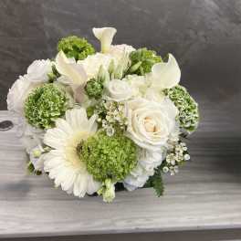 White and green floral arrangement with roses, calla lilies, and a gerbera daisy
