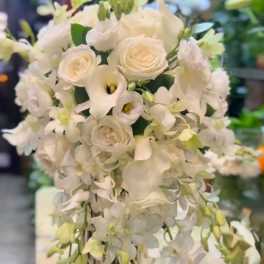 White floral arrangement with cascading orchids and roses in a vase