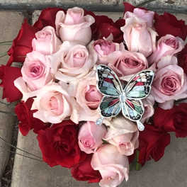 Heart-shaped bouquet of pink and red roses with a butterfly ornament