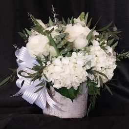 White floral arrangement in a birch-style container with a ribbon bow
