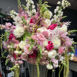 Large pink and white floral arrangement in a tall glass vase