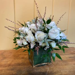 White rose arrangement in a square glass vase with greenery