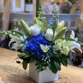 Blue hydrangea and white lilies in a white square vase