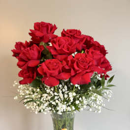 Red roses in a clear glass vase with white baby's breath