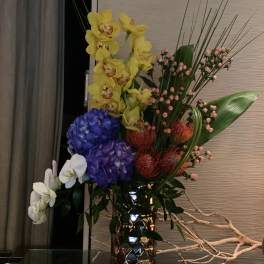 Tall mixed floral arrangement in a metallic vase with orchids and hydrangeas