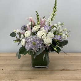 Mixed white and lavender flowers in a square glass vase
