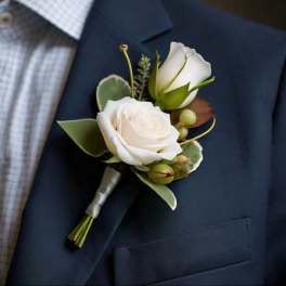 White rose boutonniere pinned to a navy suit jacket