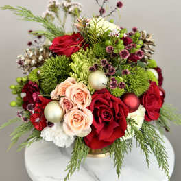 Red and peach roses with green accents in a gold vase