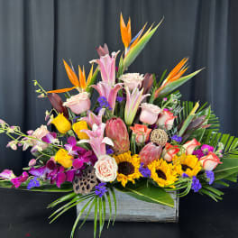 Tropical flower arrangement with lilies, roses, orchids, and sunflowers in a wooden box
