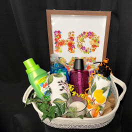 Gift basket with cleaning items, candles, and a floral "HO" sign