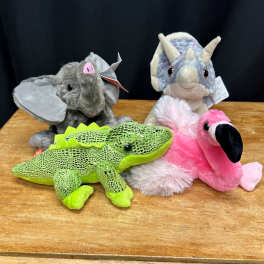 Four plush animal toys on a wooden surface.