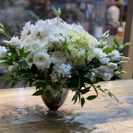 White floral arrangement in a glass vase with greenery