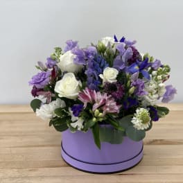 Purple and white mixed flower arrangement in a lavender box
