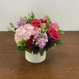 Pink and red flower arrangement in a white box vase