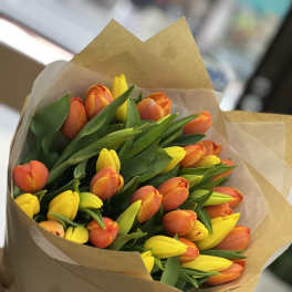 Bouquet of orange and yellow tulips wrapped in brown paper