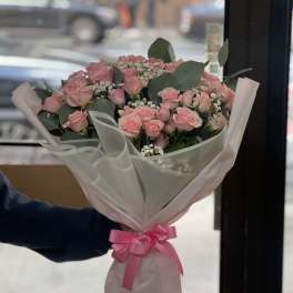 Pink rose bouquet wrapped in pale pink paper with a ribbon