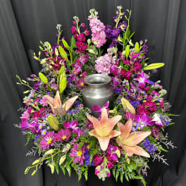 Colorful floral wreath around a silver urn on black drape