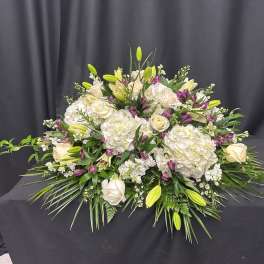 Large white floral arrangement with roses, hydrangeas, and lilies