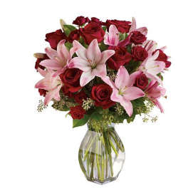 Red roses and pink lilies arranged in a clear glass vase