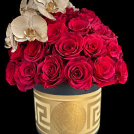Red roses arranged in a gold box with pale orchids