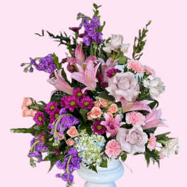 Mixed pink and purple floral arrangement in a light blue vase