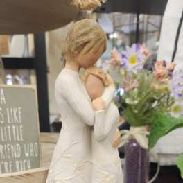 Decorative figurine of two people embracing, with a small flower arrangement behind it