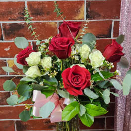 Bouquet of red and white roses in a glass vase with a pink ribbon