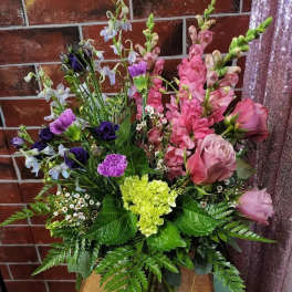 Mixed bouquet with pink roses, snapdragons, and purple blooms in a glass vase