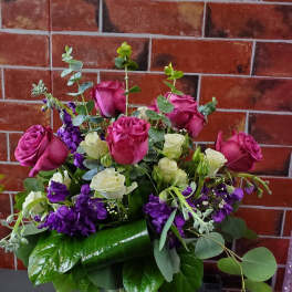 Bouquet of pink and white roses with purple flowers in a glass vase