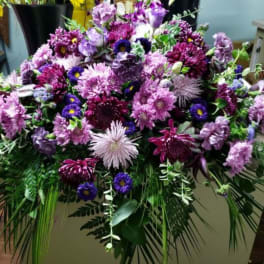 Large purple and lavender floral arrangement with cascading greenery