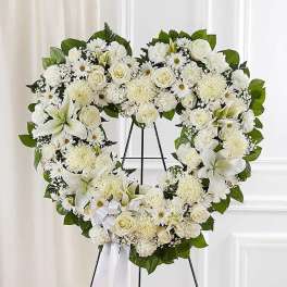 White floral heart wreath on a black stand with a ribbon bow