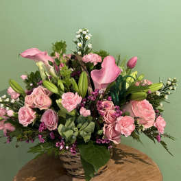 Pink roses and calla lilies arranged in a wicker basket