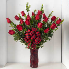 Arrangement of red roses with a red and black plaid bow in a red glass vase