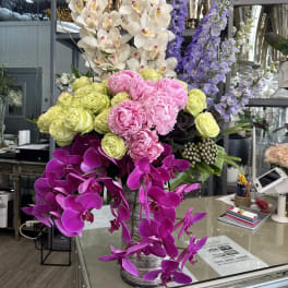 Tall arrangement of orchids, peonies, and roses in a vase