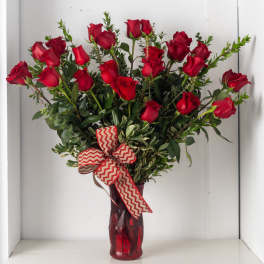 Tall arrangement of long-stem red roses in a red glass vase with chevron ribbon bow