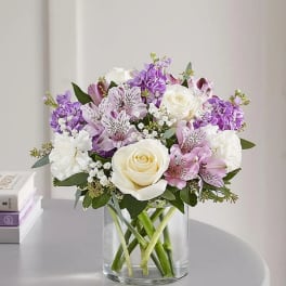 Bouquet of white roses, purple flowers, and pink lilies in a glass vase