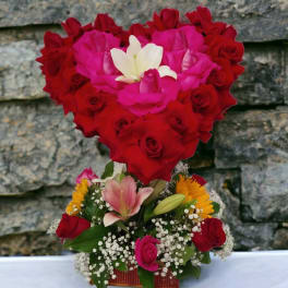Heart-shaped rose arrangement with lilies and small yellow flowers