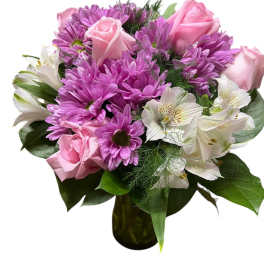 Pink roses and purple daisies arranged in a glass vase with white alstroemeria