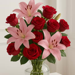 Bouquet of red roses and pink lilies in a clear glass vase