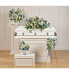 White casket with blue and white floral sprays