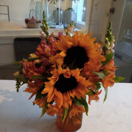 Orange sunflowers and mixed orange-pink flowers in a glass vase