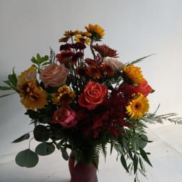 Mixed bouquet of roses and daisies in a red vase