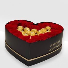 Heart-shaped black box filled with red roses surrounding gold-wrapped chocolates.