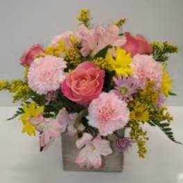 Pink and yellow mixed flower arrangement in a square vase