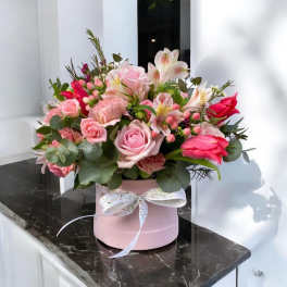 Pink and white mixed flower arrangement in a pink hat box with ribbon