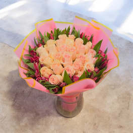 Peach roses in a glass vase with pink wrap